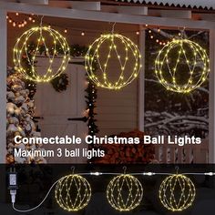 three christmas balls hanging from the side of a house with lights on them and in front of it