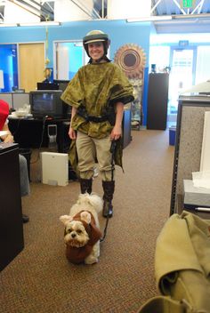 a man in an office with a dog on a leash and another person walking behind him