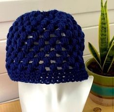 a blue crocheted hat sitting on top of a white mannequin head