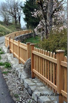 a wooden fence next to a stone wall