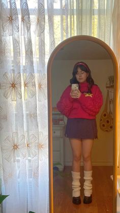 a woman standing in front of a mirror holding a cell phone and wearing knee high socks