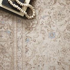 a white beaded necklace laying on top of an old rug with a book in the background