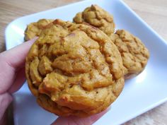 a hand holding three cookies on a white plate