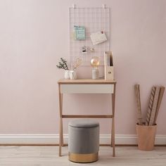 a white desk with a gray stool next to it and a pink wall in the background