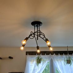 a chandelier hanging from the ceiling in a living room with windows and curtains