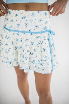 Our Desi mini skirt is the perfect summer skirt. We love the little bow detail and the blue flowers. The fabric is soft and flowy and perfect for summer days. You can even pair this skirt with a sweater and wear it into fall. How we would style it: Playful Daytime Look: Pair it with a blue tank and flip flops for a casual girly outfit. Evening Sophistication: Wear it with a tucked in blouse and ankle boots for a chic night out. Boho Vibes: Team it with a cropped knit sweater and cowboy boots for a trendy, bohemian-inspired ensemble. Where we would wear it: Garden Party: Ideal for a little garden party with its flowy silhouette. Brunch Date: Perfect for a stylish yet comfortable look when meeting friends for brunch. Art Gallery Visit: Stand out with this pretty, polished outfit while explor Summer Mini Skirt With Mini Hem For Day Out, Chic Ditsy Floral Print Skirt For Spring, Chic Ditsy Floral Print Summer Skirt, Spring Mini Length Skort For Day Out, Summer Flared Mini Skirt For Brunch, Summer Mini Hem Skort With Relaxed Skirt, Summer Mini Hem Skort, Flared Mini Skirt For Summer Brunch, Summer Daywear Fitted Skort