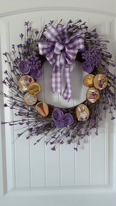 a wreath with purple flowers and wooden buttons hanging on the front door to decorate it