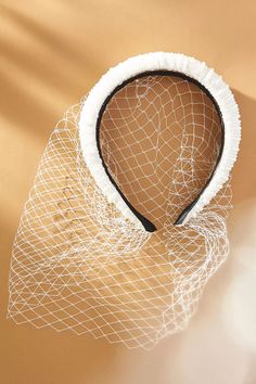 a close up of a white net on a tan background with a black and white headband