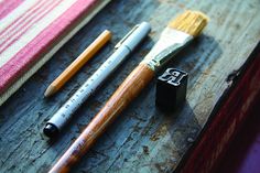 three different types of pens and brushes sitting on a table next to a striped towel