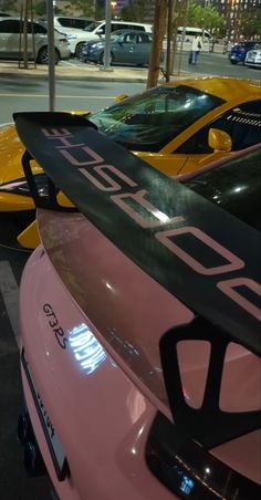 a pink sports car with a surfboard on the hood is parked next to other cars