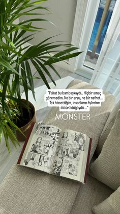 an open book sitting on top of a couch next to a plant