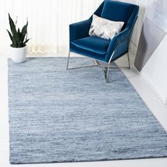 a blue chair sitting on top of a white floor next to a rug and potted plant