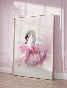 a white swan with a pink bow on it's back sitting in front of a wall