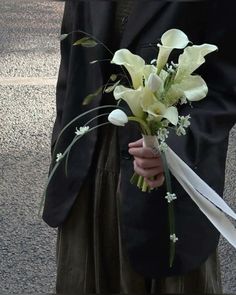 a man in a suit holding a bouquet of flowers and an umbrella on the street