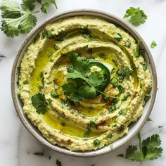 a bowl filled with hummus and cilantro garnished with parsley