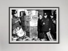 black and white photograph of men in uniform standing next to stacks of boxes with drinks on them