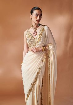 Ivory georgette pre-stitched sari featuring gold cutwork embroidery on the border, accompanied by a fully embroidered blouse. Cream Pre-draped Saree With Dupatta, Festive Cream Georgette Pre-draped Saree, Designer Gold Sharara With Embroidered Border, Elegant Off White Saree, Elegant Off White Pre-draped Saree With Zari Work, Anarkali Style Pre-draped Cream Saree, Anarkali Style Cream Pre-draped Saree, Elegant Off White Saree With Zari Work, Elegant Off White Saree For Reception