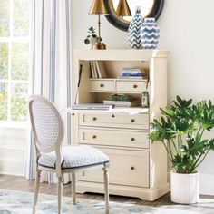 a room with a chair, desk and mirror on the wall next to a potted plant