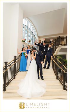 a bride and groom walking down the stairs with their bridal party in the background