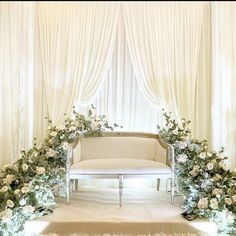 a white couch sitting under a window covered in flowers and greenery on top of a rug