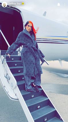 a woman with red hair standing on the steps of an airplane