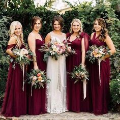 a group of women standing next to each other wearing dresses and holding bouquets in their hands