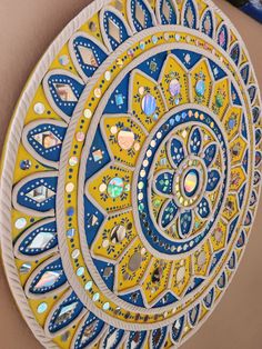 a yellow and blue plate with designs on it's side next to a woman's stomach