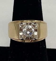 a yellow gold ring with a diamond in the center on a black velvet display stand