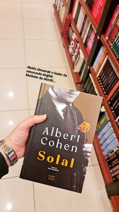 a person holding up a book in front of bookshelves