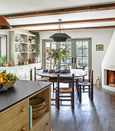 an open kitchen and dining room with wood flooring, white walls and ceiling beams