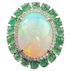 A statement Opal and Colombian Emerald cabochon cocktail ring, with White Diamonds. This enchanting ring combines the lush green of emerald with the captivating beauty of an oval-shaped opal at its heart. Details: 18K Gold - 8.13 Grams Diamond Round - 0.23 carat Emerald - 2.59 Carat Opal -5.64 Cts Opal Emerald Diamond Ring, Fine Jewelry Green Cabochons For Formal Occasions, Green Gemstone Cabochons For Formal Use, Green Cabochons For Formal Fine Jewelry, Fine Jewelry Green Emerald Cabochon Ring, Fine Jewelry Green Cabochon Emerald Ring, Green Cabochon Emerald Ring Fine Jewelry, Elegant Green Cabochon Emerald Ring, Elegant Green Emerald Cabochon Ring