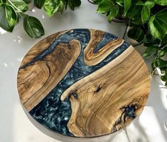 a wooden plate sitting on top of a white table next to a potted plant