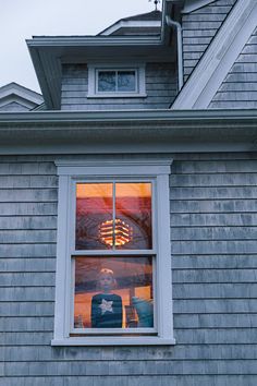 a woman is looking out the window at her reflection in the house's windows