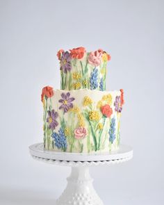 a three layer cake with flowers painted on it