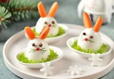 three small carrot bunnies with bunny ears on them sitting in small white bowls filled with lettuce and carrots