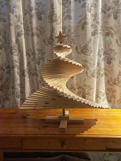 a wooden table with a sculpture on top of it next to a curtained window