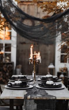 the table is set with black plates and candles