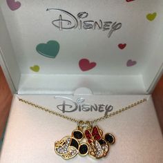 the disney necklace is in its box and has two hearts attached to it, along with other charms