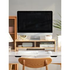 a computer monitor sitting on top of a desk next to a wooden chair and table