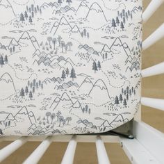 a white crib with mountains and trees on it