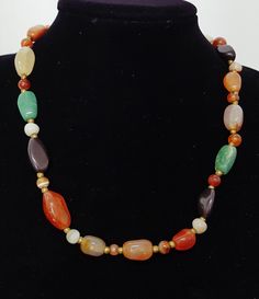 Vintage 60s Mixed Gemstone Necklace of Natural Mixed Hand Polished Seni Precious Beaded Stones Necklace with brass spacer beads and a brass barrel closure. Features 35 assorted natural irregular polished and round polished gemstones including agates, onyx, carnelian, quartz, and chrysoprase. Georgeous earthy coloured gem assortment in a lovely length to compliment any outfit. Quality stones in a classically balanced bead composition. Era: 70's Condition: Excellent Composition: Asorted polished g Vintage Jade Beaded Necklace, Vintage Multicolor Gemstone Beads And Cabochons, Multicolor Carnelian Beaded Jewelry, Handmade Vintage Multicolor Beads, Gems, And Cabochons, Multicolor Carnelian Jewelry With Polished Beads, Vintage Natural Stones Beaded Necklaces, Vintage Beaded Necklaces With Natural Stones, Vintage Multicolor Necklaces With Natural Stones, Vintage Multicolor Natural Stones Necklace