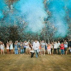 a group of people standing on top of a grass covered field under blue and green fireworks