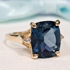 a fancy ring with a blue stone surrounded by two diamonds on a white cloth background