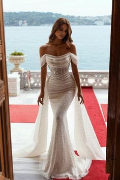 a woman in a white dress is standing on a red carpet and looking at the camera