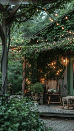 an outdoor patio with lights strung over it and chairs on the outside deck, surrounded by greenery