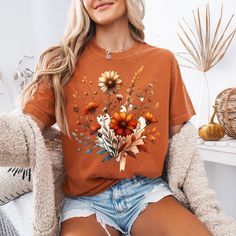 a woman sitting in a chair wearing a t - shirt with flowers on it