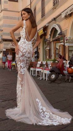 a woman in a white dress is standing on the street with her back to the camera