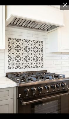 a stove top oven sitting inside of a kitchen next to a wall with tile on it