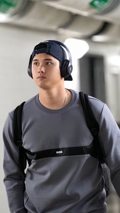 a young man with headphones on walking in an airport hallway, looking at the camera