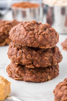 three chocolate cookies stacked on top of each other with peanut butter in the back ground